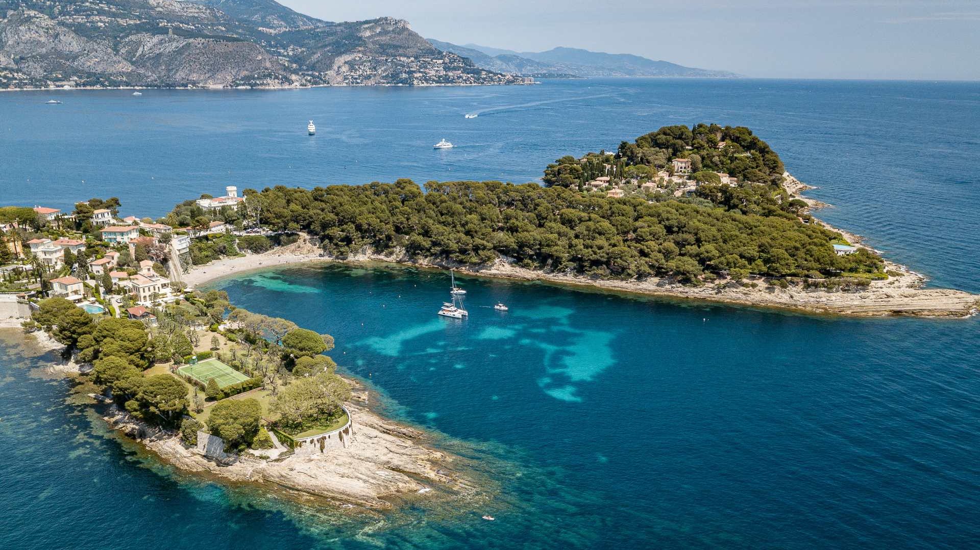 Drohnenaufnahme vom Cap Ferrat, einer Halbinsel vor der franzÃ¶sischen KÃ¼ste im Mittelmeer. TÃ¼rkisfarbenes Wasser und eine grÃ¼ne Insel. 
